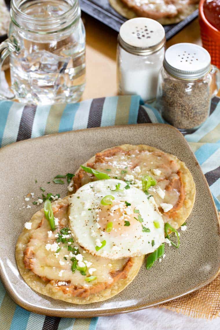 Breakfast tostadas topped with refried beans and a fried egg.