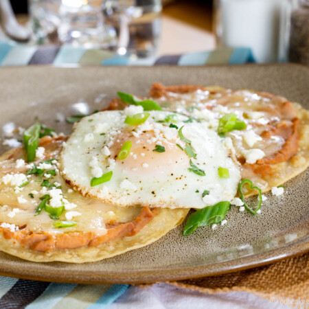 Breakfast tostadas topped with refried beans and a fried egg.