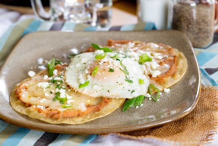 Breakfast tostadas topped with refried beans and a fried egg.