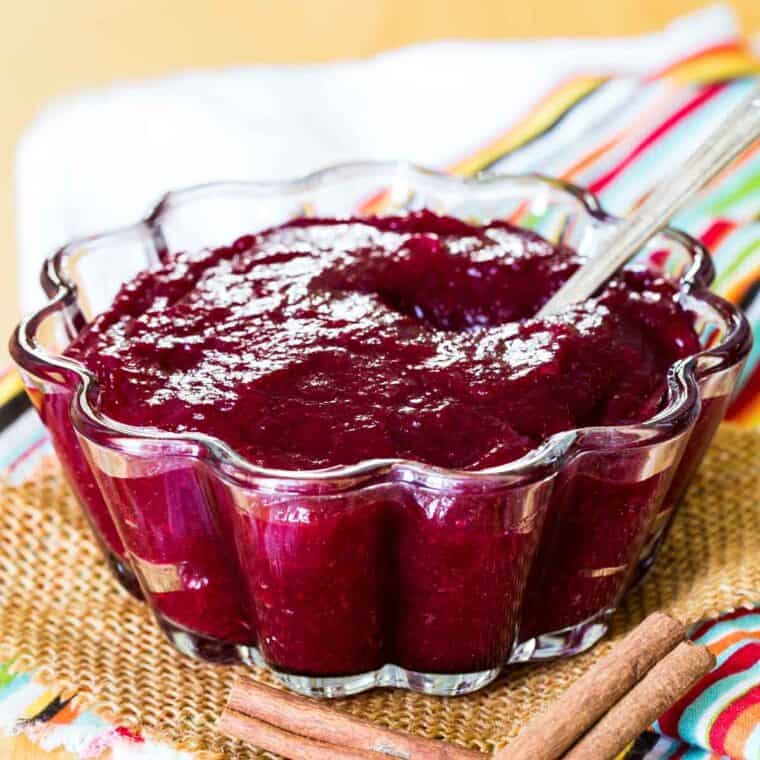 Cinnamon orange cranberry sauce in a scalloped glass bowl with a spoon.