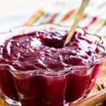 Cinnamon orange cranberry sauce in a scalloped glass bowl with a spoon.