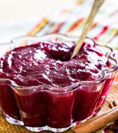 Cinnamon orange cranberry sauce in a scalloped glass bowl with a spoon.