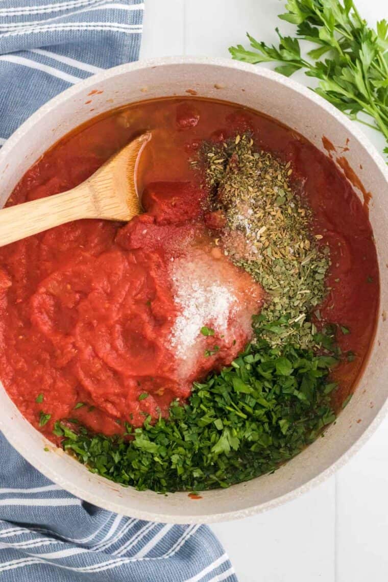 Adding tomato sauce and spices to a pot