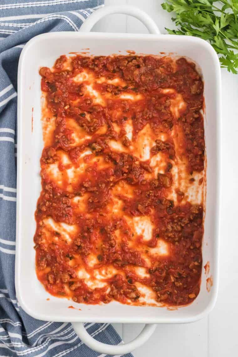 Pasta sauce spread on the bottom of a baking pan