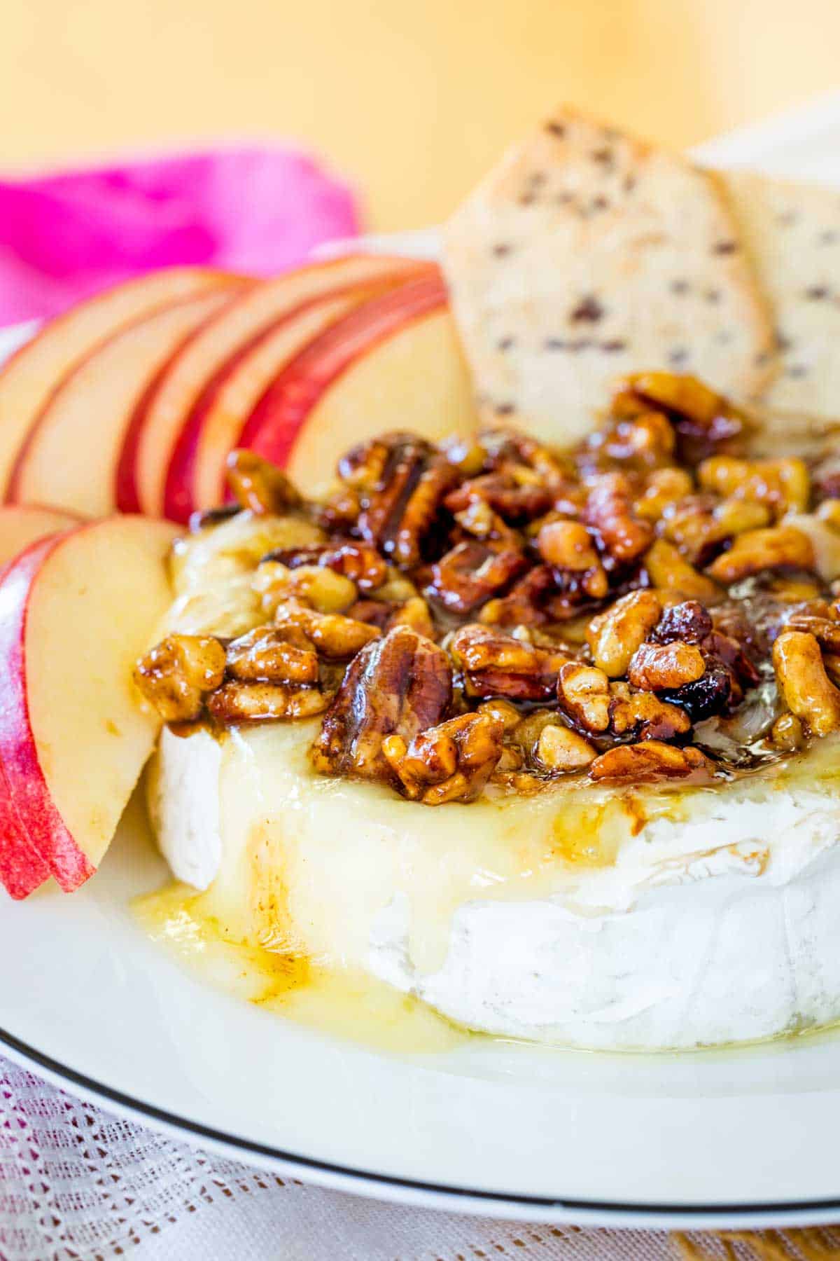 A round of honey nut baked brie with some of the cheese oozing onto the plate
