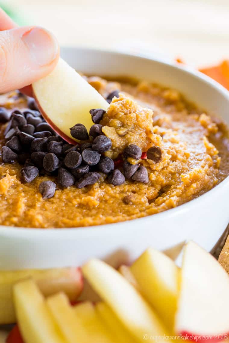 Dipping an apple in Chocolate Chip Pumpkin Hummus