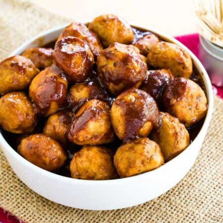 A white bowl of turkey meatballs covered in barbecue sauce.
