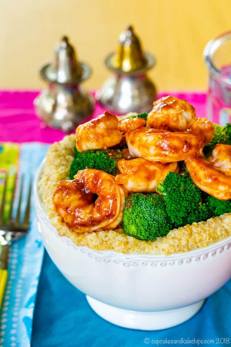 Shrimp in barbecue sauce and steamed broccoli served on top of a bowl of cheesy quinoa.