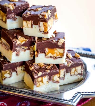 A pile of squares of snickers fudge on a silver platter.
