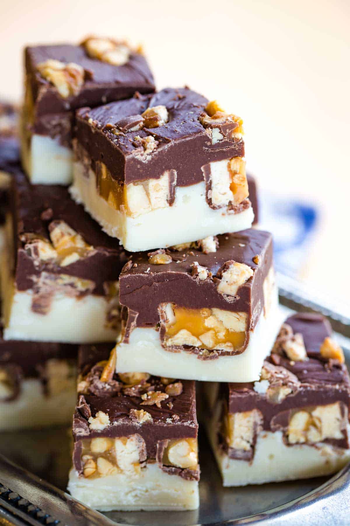 Squares of Snickers fudge stacked on a tray.