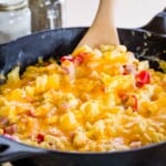 pan of fluffy scrambled eggs with cheese, tomatoes, pineapple and ham