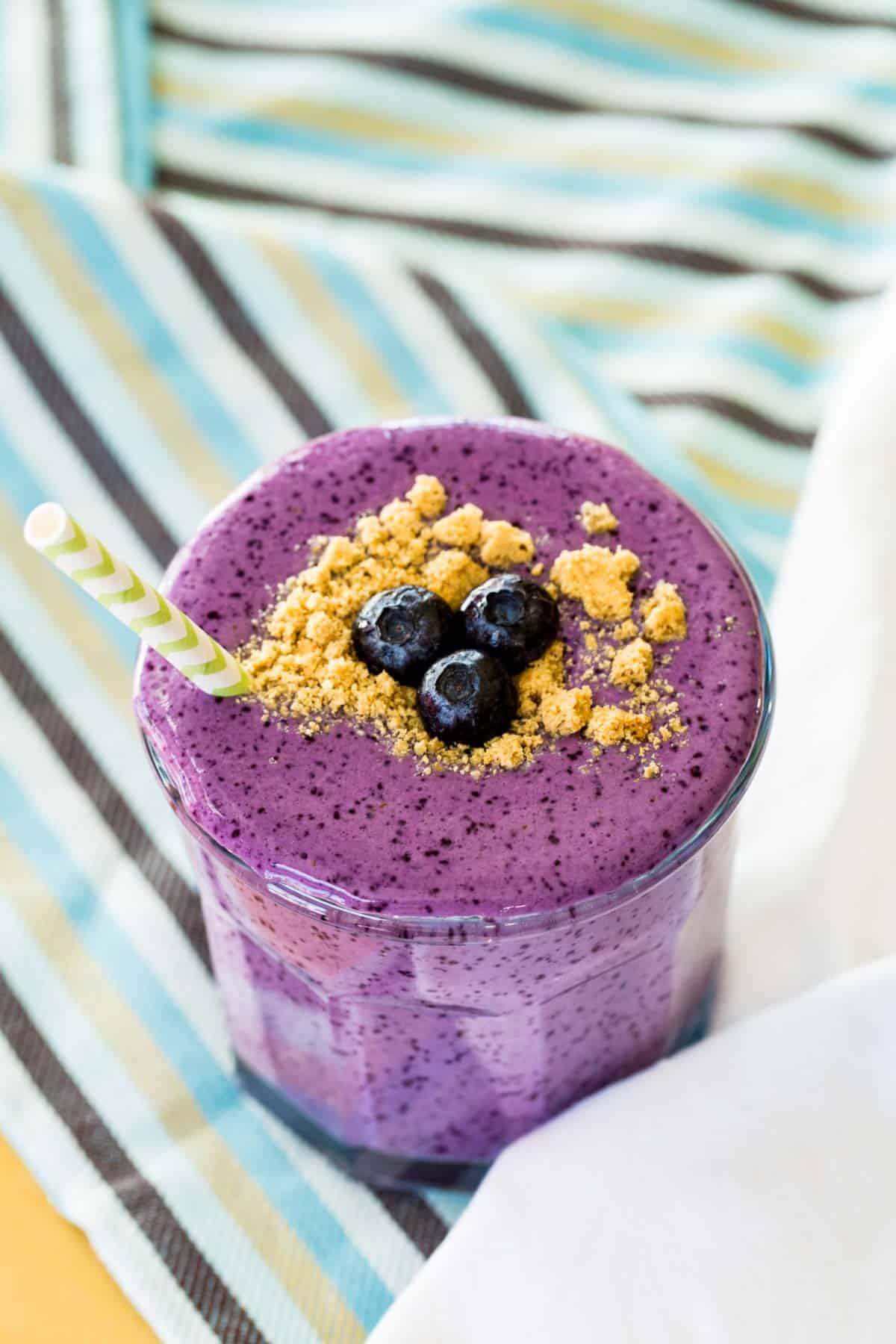 Blueberry Cheesecake Smoothie in a glass on a blue and brown striped napkin