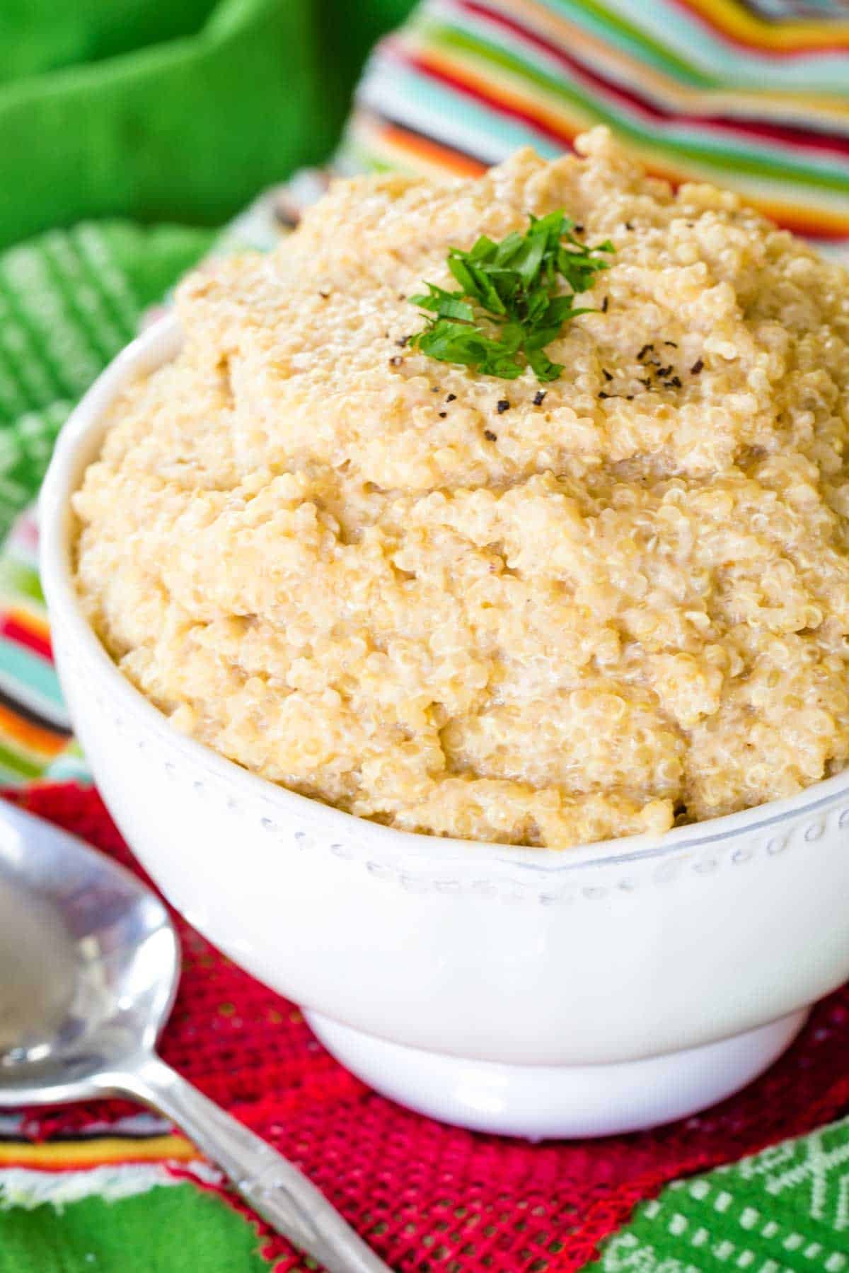 A bowl of a cheesy quinoa side dish on a green napkin.