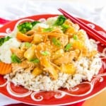 Pineapple Teriyaki Chicken Over rice on a red and white plate with red chopsticks