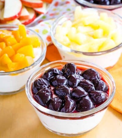 Yogurt dip topped with cherries, pineapples, and peaches.