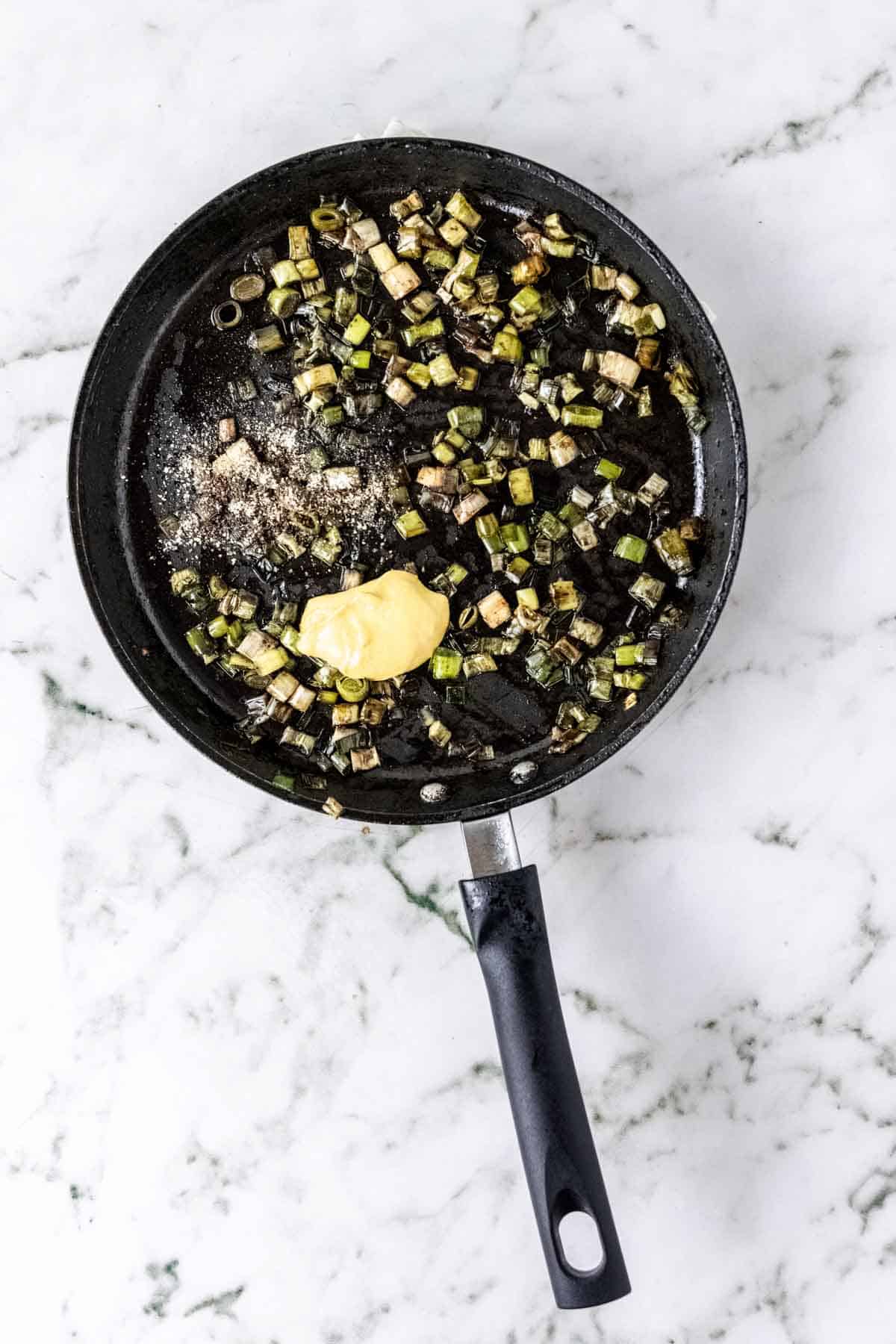 Dijon mustard is added to a skillet with caramelized leeks.