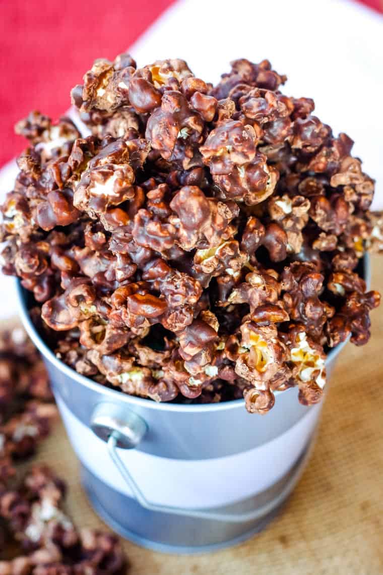 Bourbon Pecan Chocolate Popcorn overflowing form a small tin bucket