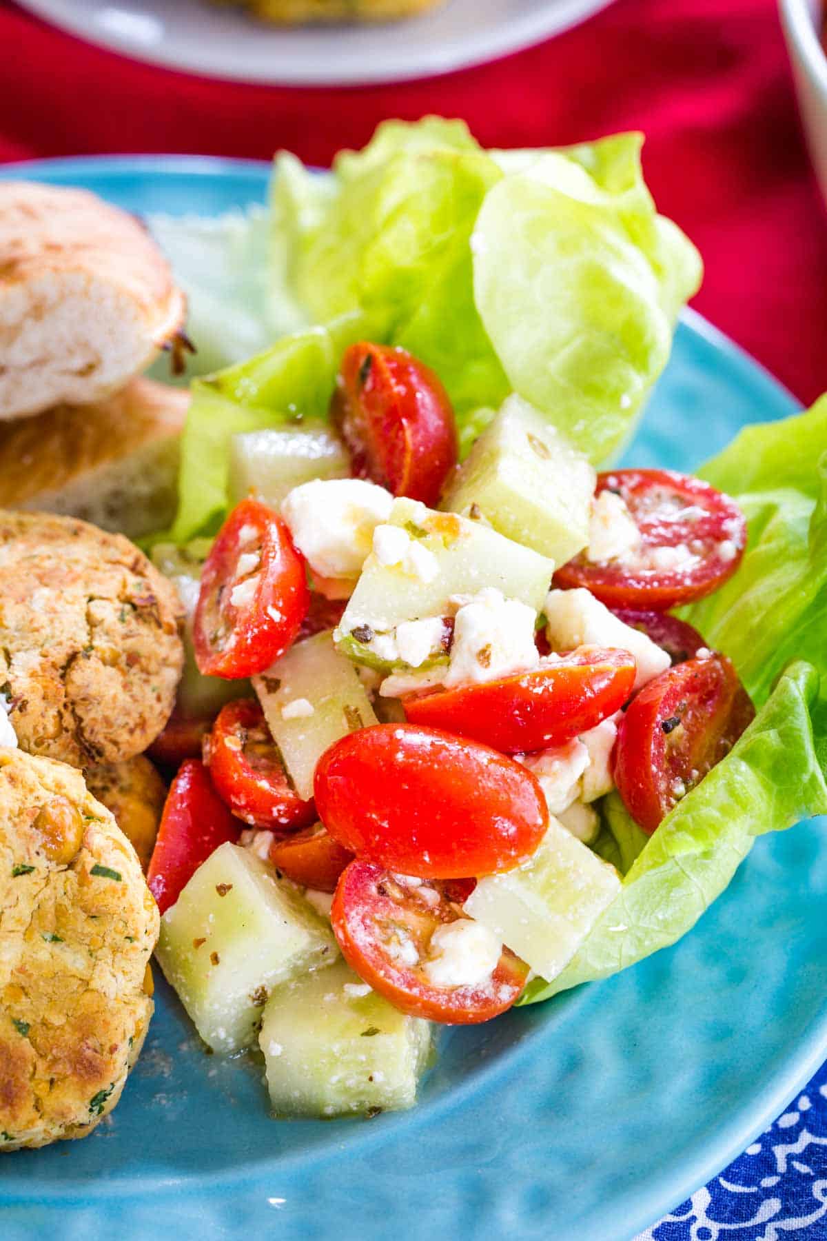 Tomato Cucumber Salad with feta and a lemon oregano dressing on a blue plate with falafel