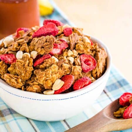 A bowl and a spoon with peanut butter and jelly granola