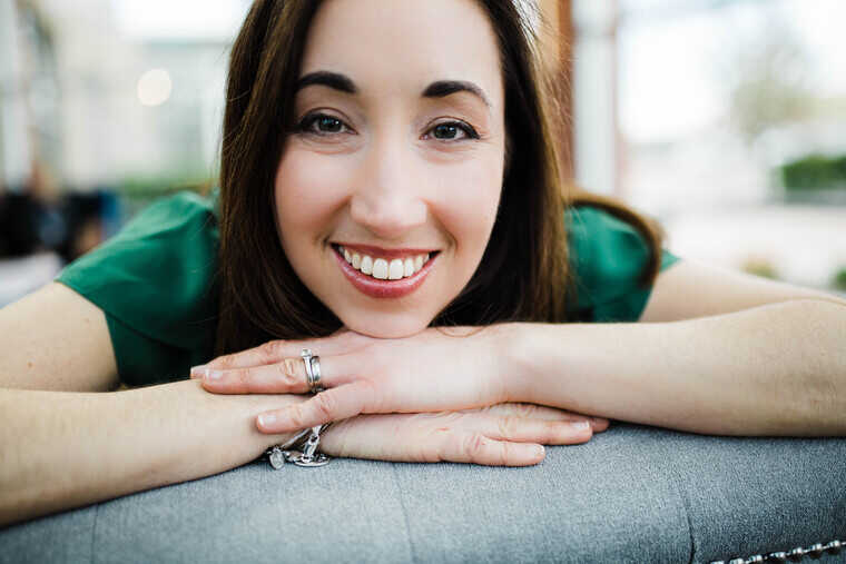 smiling woman with head resting on her hands