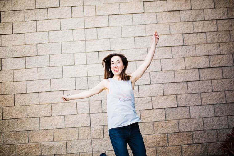 woman jumping in front of a brick wall