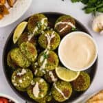 Overhead view of a bowl of baked falafel drizzled with tahini