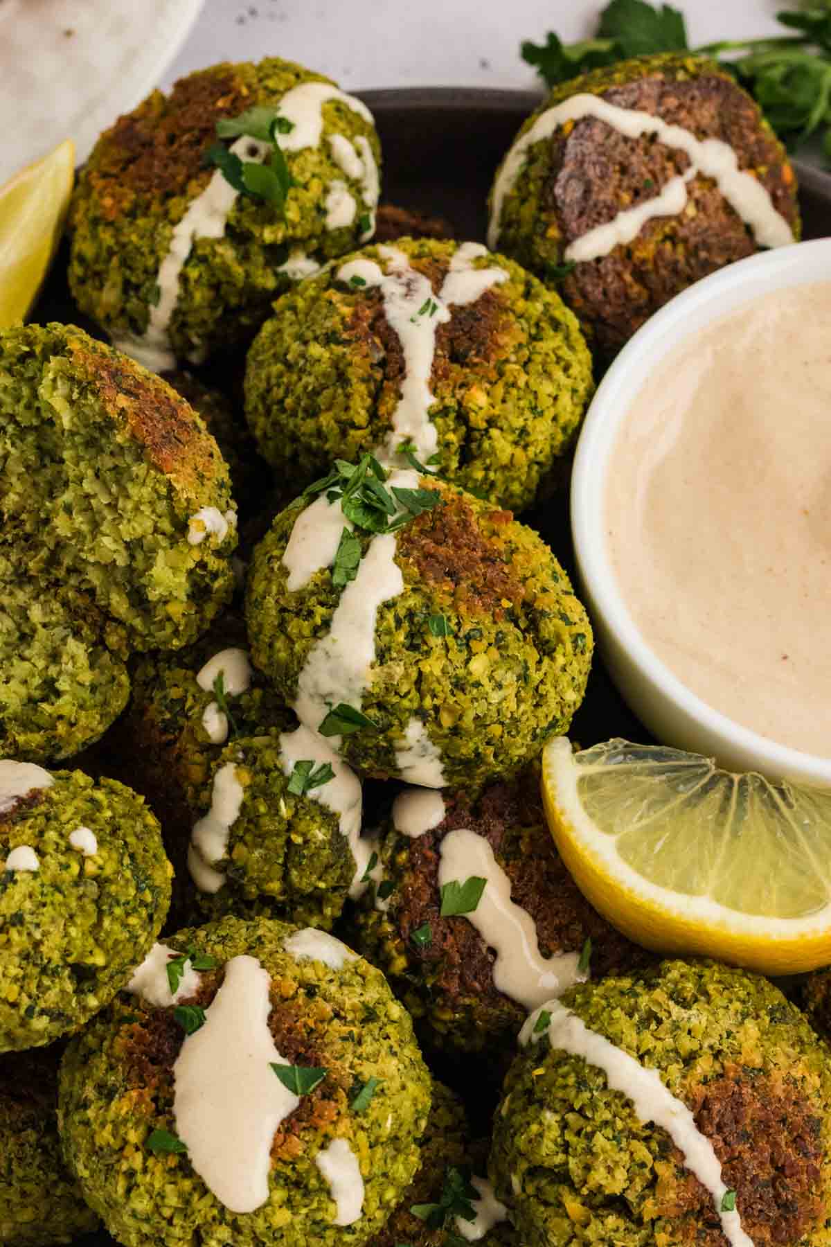 Close up of a bowl of falafel drizzled with tahini