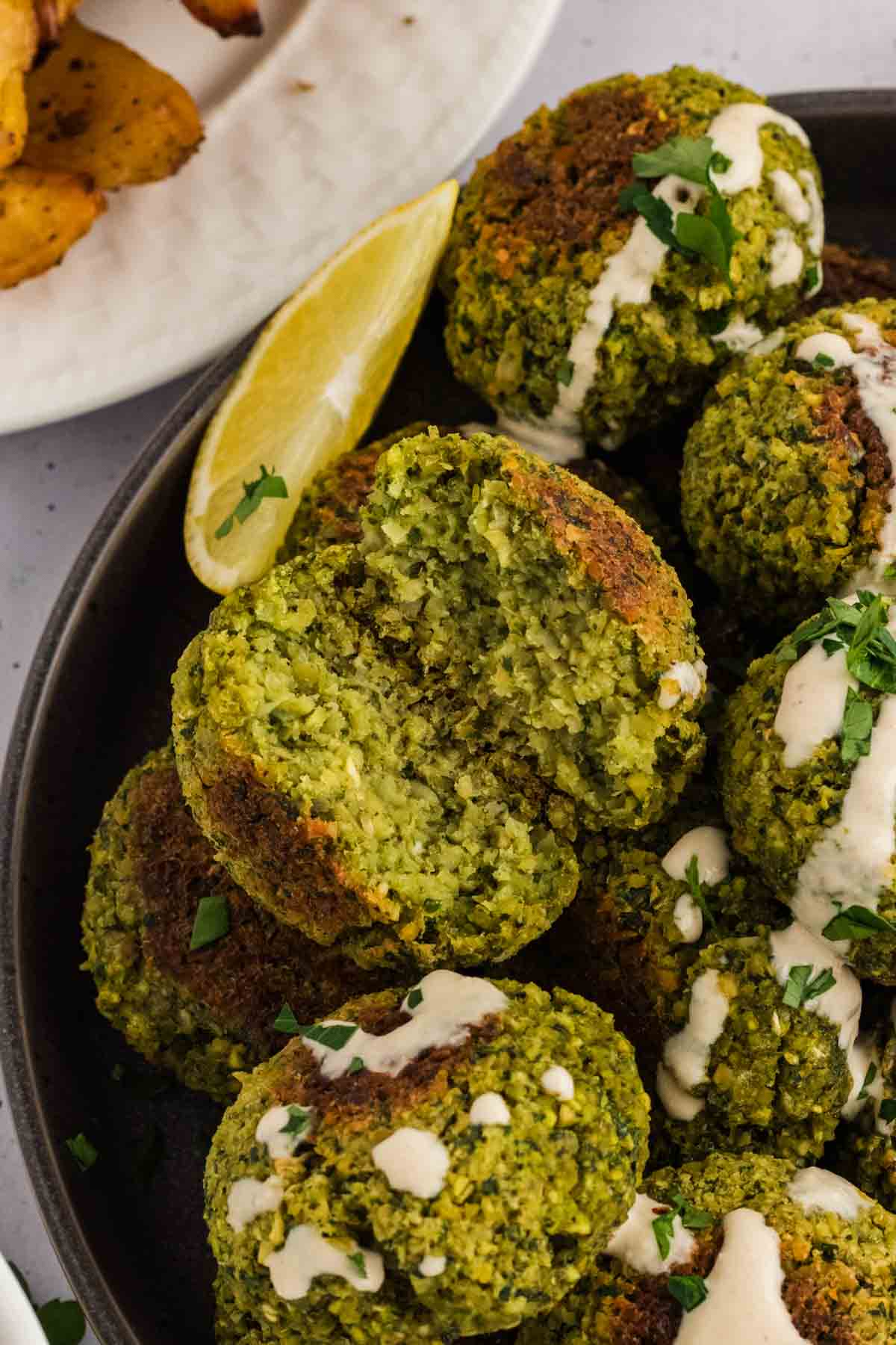Close up of a bowl of falafel with one cut in half to show the inside