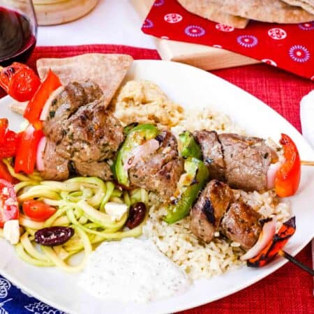 Brochetas de ternera griega con tzatziki, pita, arroz y ensalada griega de zoodles