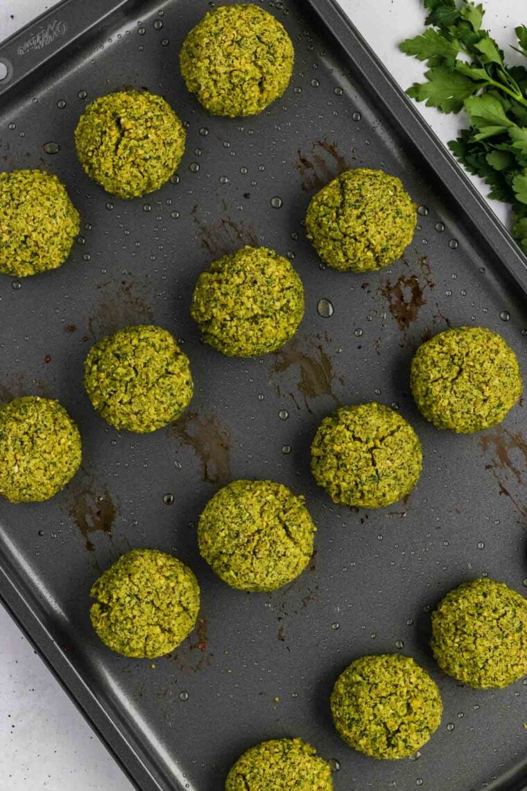 Partially cooked baked falafel on a baking sheet