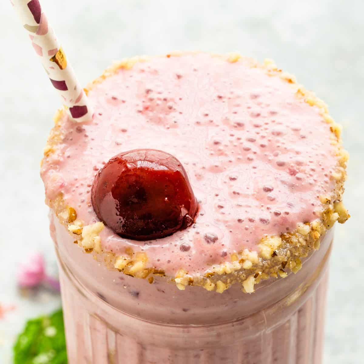 A cherry floating on top of a Cheesecake Cherry Smoothie.