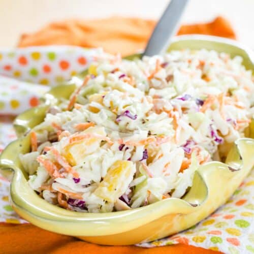 Hawaiian Pineapple Coleslaw in a yellow dish with fluted edges and a spoon in it.