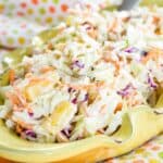Hawaiian Coleslaw with pineapple in a yellow bowl on a polka dot and orange cloth napkins.