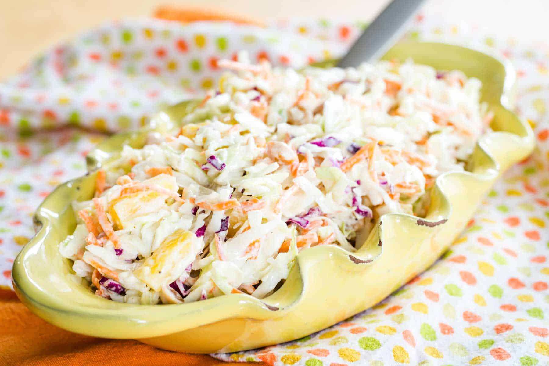 Hawaiian Pineapple Coleslaw in an oval bowl on a polka dot napkin.