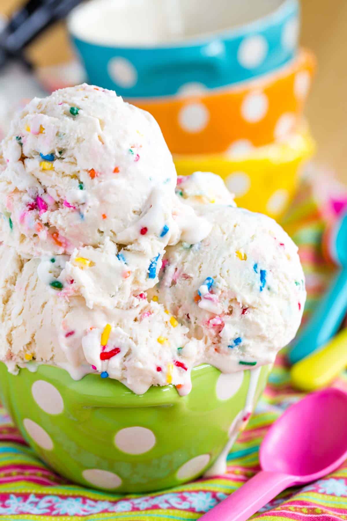 Funfetti Cake Batter Ice Cream in a green polka dot bowl with a pink plastic spoon next to it.
