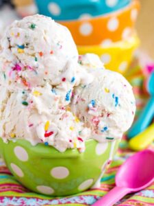 Funfetti Cake Batter Ice Cream in a green polka dot bowl with a pink plastic spoon next to it.