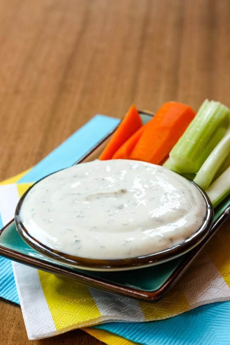 Greek Yogurt Ranch Dip with veggies on a plate on top of a stack of colorful napkins.