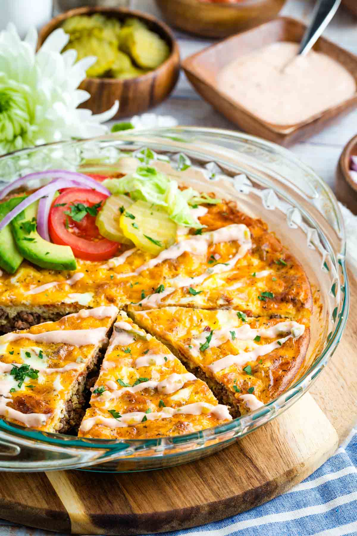 A bacon cheeseburger crustless quiche with a few pieces lsiced