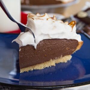 A slice of s'mores pudding pie on a blue plate with a fork in it.