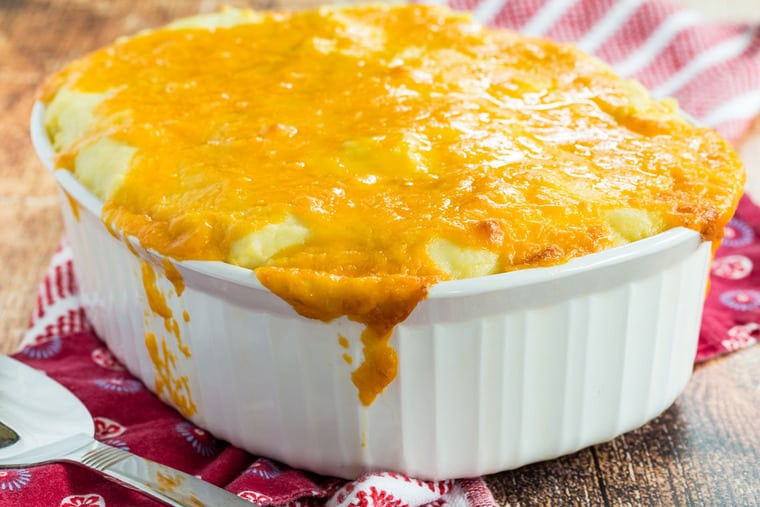 A white baking dish with Low Carb Shepherd's Pie and cheese on top and down the sides