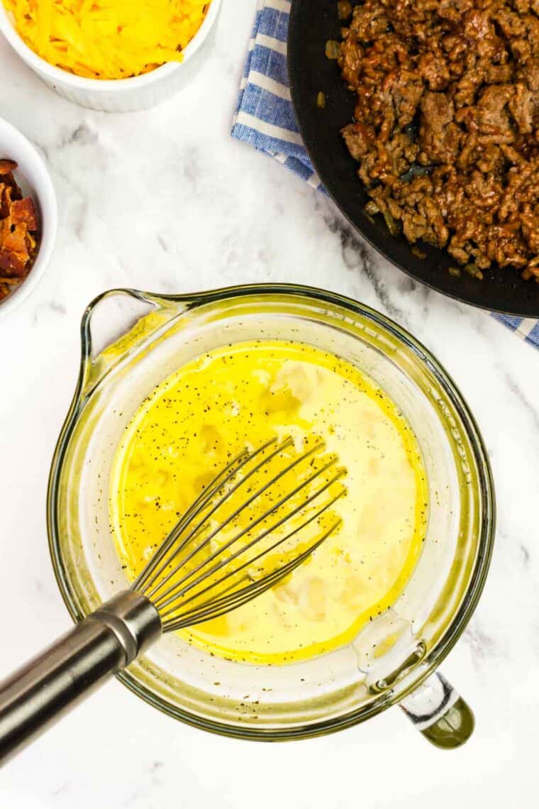 Bacon Cheeseburger Crustless Quiche is made with ground beef, bacon, and cheese, plus your favorite burger toppings. Whisking scrambled eggs