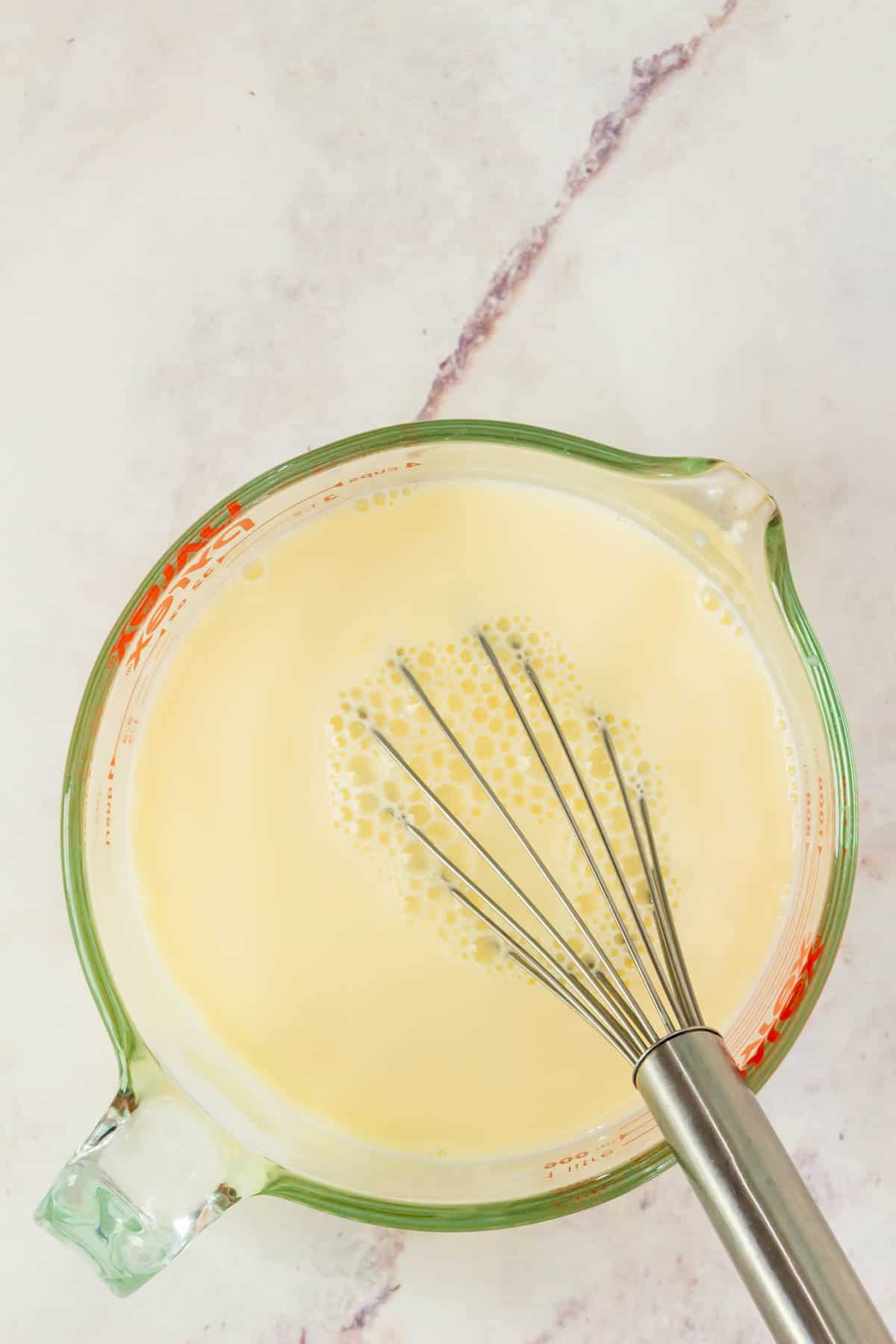 Egg yolks and milk whisked together in a large measuring cup.