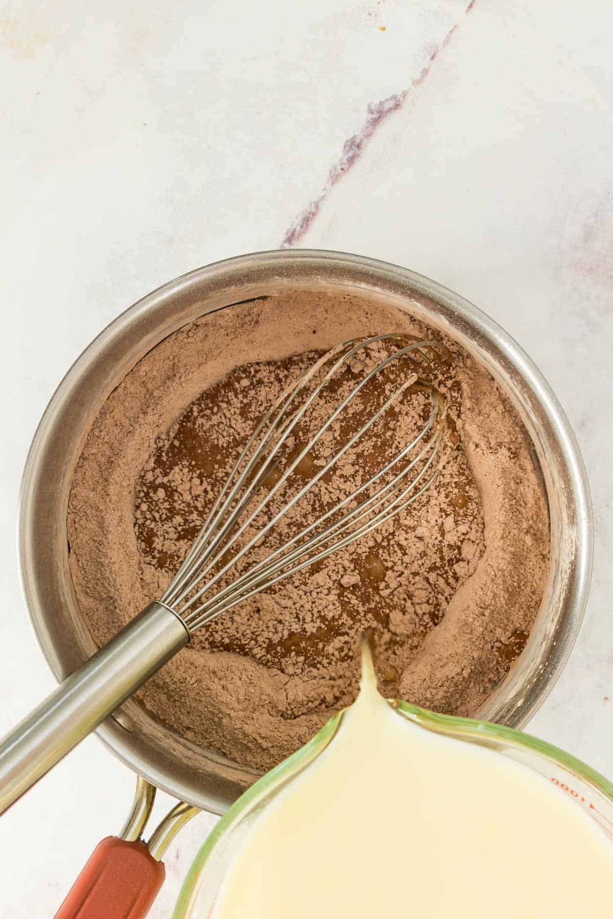 Milk mixture is added into a saucepan with sugar and cocoa powder.