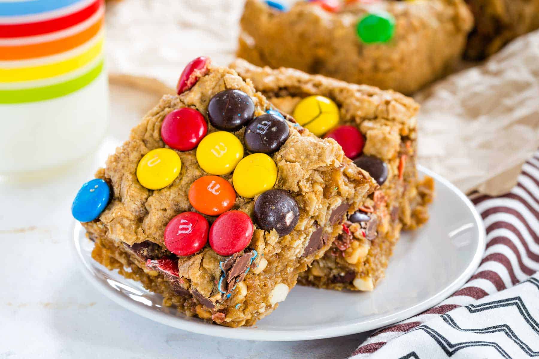 A stack of two No Flour Monster Cookie Bars on a small white plate