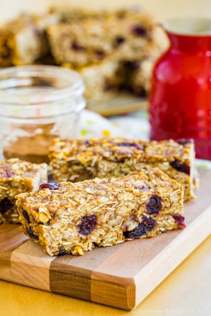 A pumpkin granola bar with cranberries and nuts on a cutting board