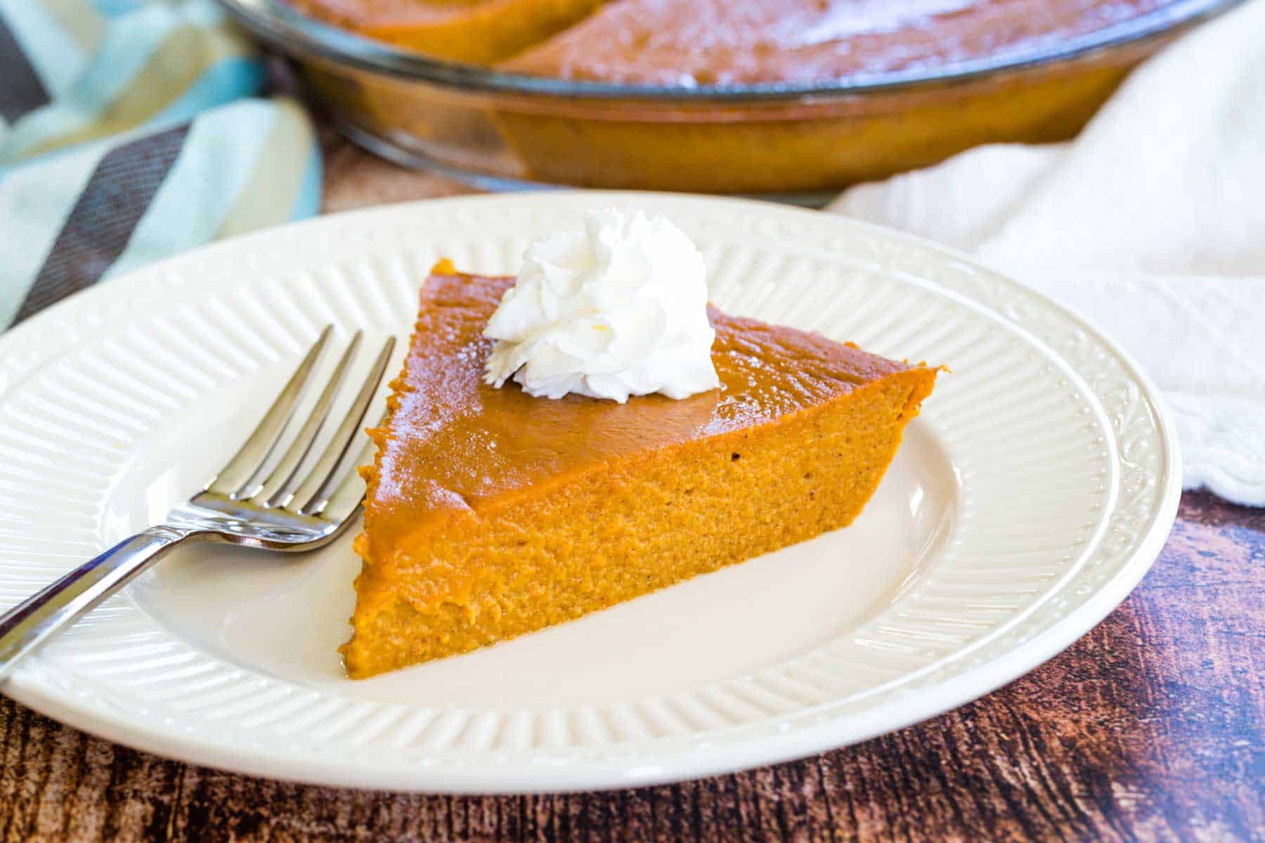 A piece of no crust pumpkin pie with whipped cream on a plate