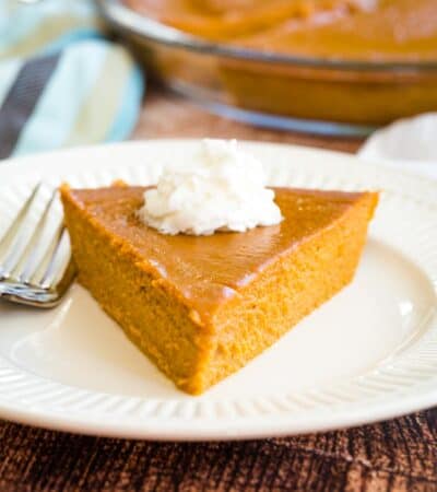 Crustless Pumpkin Pie slice on a plate with whipped cream.