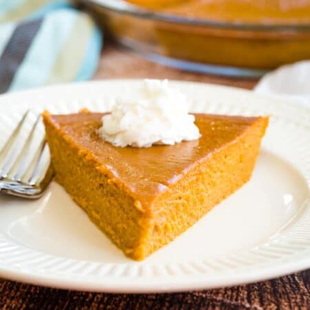 Crustless Pumpkin Pie slice on a plate with whipped cream.