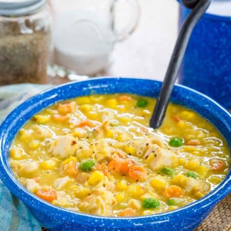 A blue bowl of Chicken and Corn Chowder with a soup spoon.