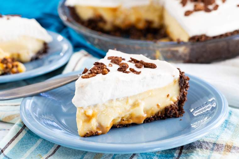 Dulce de Leche Banana Cream Pie slice on a plate with whole pie in background